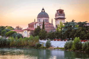 A serene river flowing under a picturesque bridge, with a charming church in the background