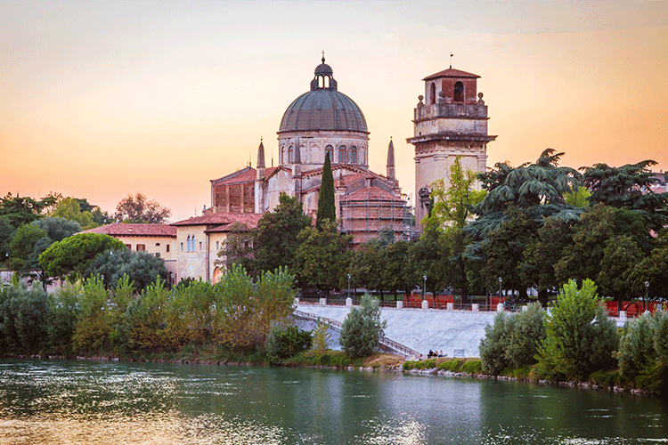A serene river flowing under a picturesque bridge, with a charming church in the background