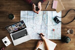Two friends discussing travel plans, looking at a map and guidebook