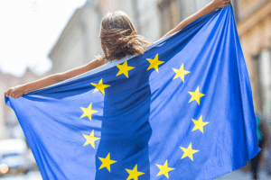 A woman proudly holds the EU flag in the street, symbolizing her support for the European Union