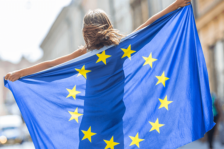 A woman proudly holds the EU flag in the street, symbolizing her support for the European Union