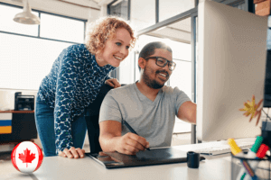 A man and woman focused on a computer screen, engrossed in their work together