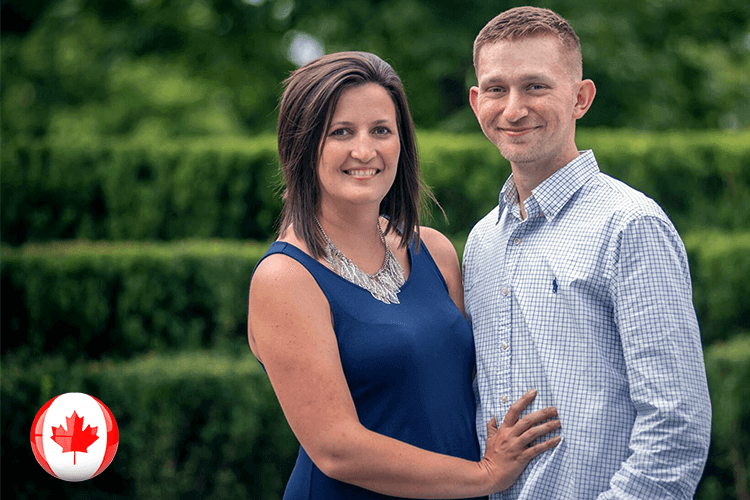 A couple smiling in front of a Canadian flag, capturing a joyful moment together