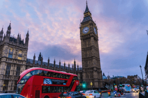 A red double decker bus driving down a street in London